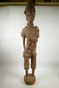 An African carved wood and dung mortar figure with shell and bead details, 40" high, A/F