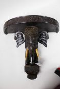 An Oriental carved ebonised wall bracket carved as a elaborately dressed elephant, 13" wide, 11½"