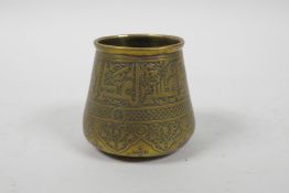 An Islamic brass pot with script decoration, 2½" high