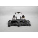 A C19th ebony desk stand with twin glass inkwells with ebony lids, and finely carved swag and floral