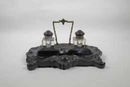 A C19th ebony desk stand with twin glass inkwells with ebony lids, and finely carved swag and floral