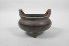 A Chinese bronze censer on tripod feet with two phoenix eye handles, impressed character marks to