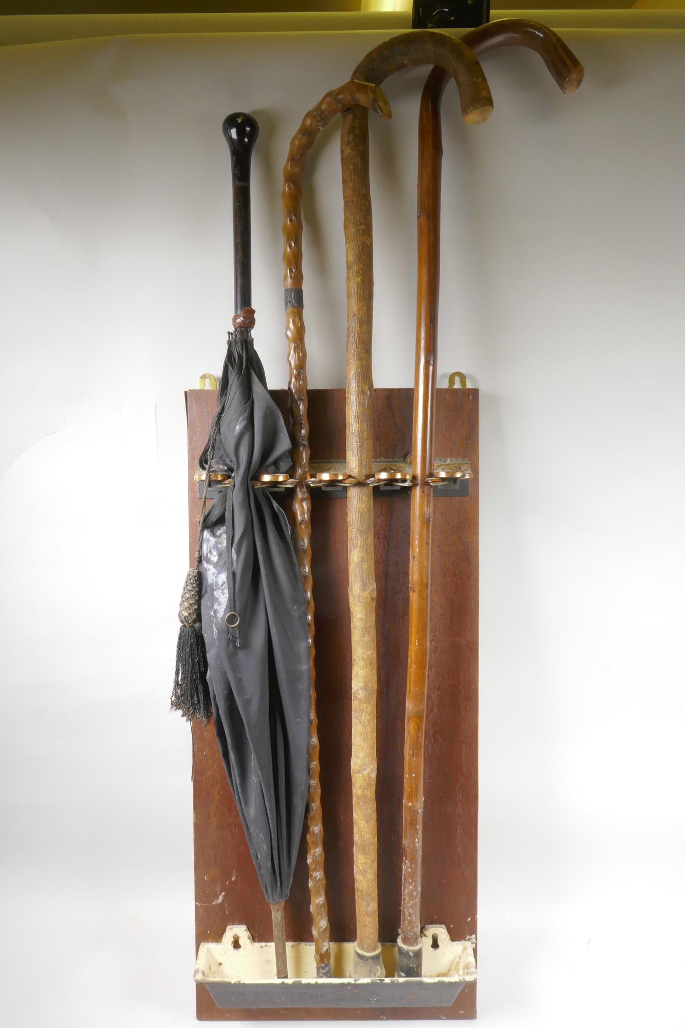 A C19th wall mounted stick stand with patent locking mechanism containing three walking sticks and
