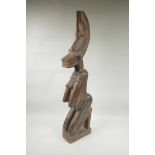 An African carved hardwood nude figure with a crescent moon shaped face, 30½" high