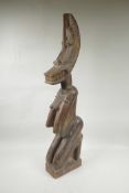 An African carved hardwood nude figure with a crescent moon shaped face, 30½" high