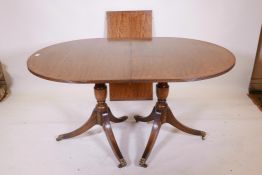 A mahogany twin pedestal dining table, raised on turned columns and splay supports, with extra leaf,