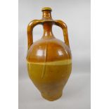 An antique treacle glazed wine jar with two handles and narrow neck, A/F, 20½" high