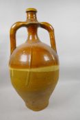 An antique treacle glazed wine jar with two handles and narrow neck, A/F, 20½" high