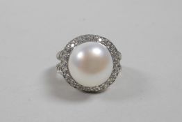 A silver dress ring set with a large freshwater pearl encircled by cubic zirconium, approximate size