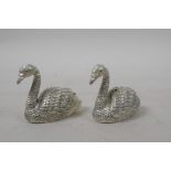 A pair of silver plated condiments in the form of swans with ruby set eyes, 1½" long