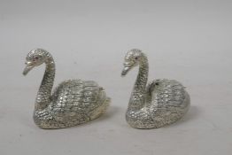 A pair of silver plated condiments in the form of swans with ruby set eyes, 1½" long