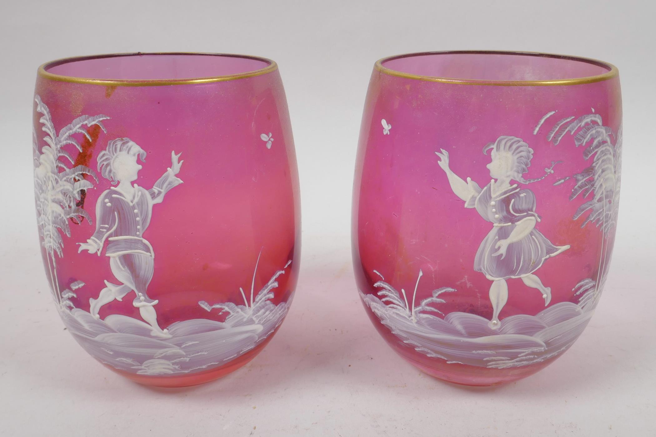 A pair of cranberry glass tumblers with Mary Gregory style decoration of young children and a