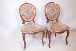 A pair of C18th walnut side chairs with spoon shaped backs and fine carved decoration, raised on