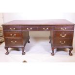An Edwardian mahogany six drawer pedestal desk with two brushing slides, raised on cabriole supports