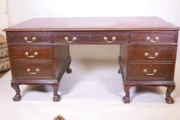 An Edwardian mahogany six drawer pedestal desk with two brushing slides, raised on cabriole supports