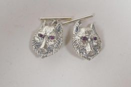 A pair of silver cufflinks in the form of wolf heads