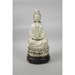 A Chinese blanc de chine porcelain Quan Yin seated on a lotus flower, on a carved and pierced