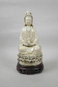 A Chinese blanc de chine porcelain Quan Yin seated on a lotus flower, on a carved and pierced