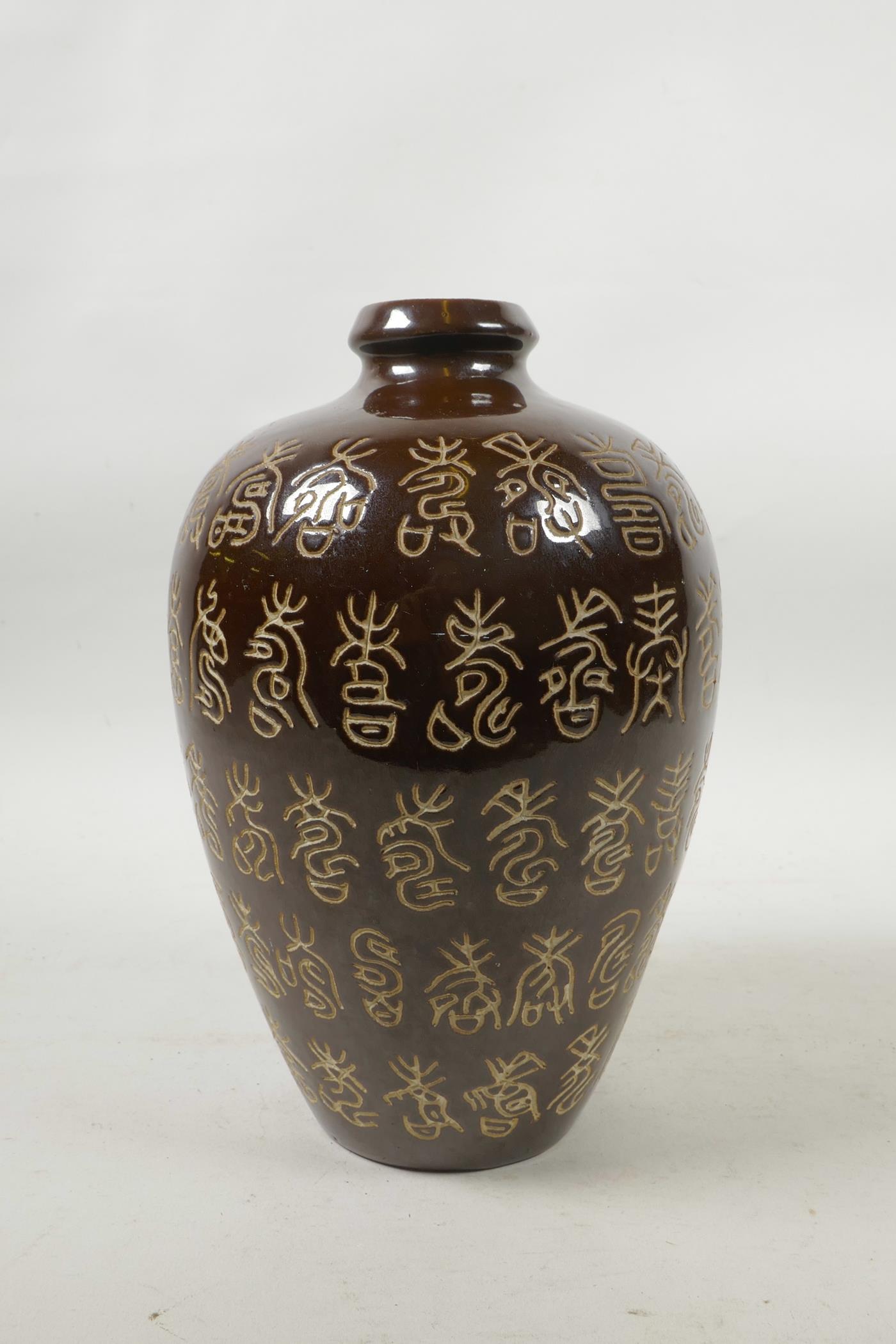 A Chinese treacle glazed porcelain vase with all over chased inscription decoration, 8½" high