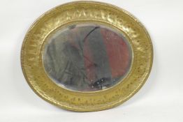 A C19th oval bevelled glass pier glass mirror in a hammered brass frame, 11" x 13" overall