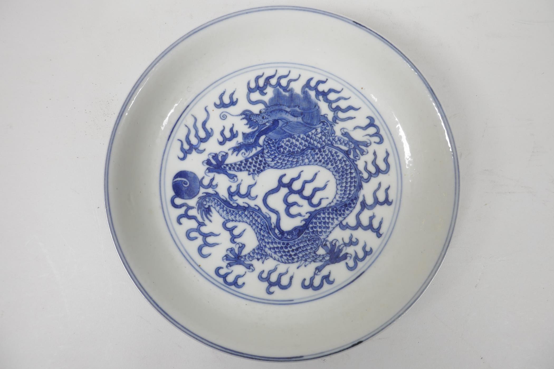 A Chinese blue and white porcelain cabinet dish decorated with a dragon chasing the flaming pearl,