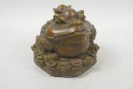 A Chinese filled bronze figure of a three footed toad (Chan-Chu) sitting on a pile of coins,