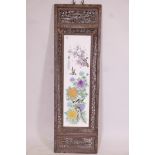 A Chinese famille rose porcelain panel in a carved and pierced hardwood frame, decorated with