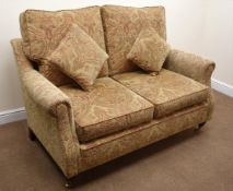 Two seat sofa upholstered in beige floral patterned chenille fabric, turned supports,