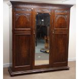 Early 20th century oak triple wardrobe, projecting cornice above three doors with carved detailing,