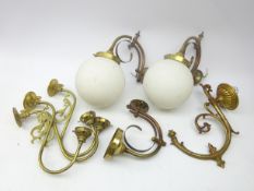 Three brass scroll wall lights, two with globular opaque glass shades,