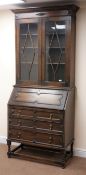 Early 20th century oak bookcase on bureau, projecting cornice, two glazed doors, three shelves,