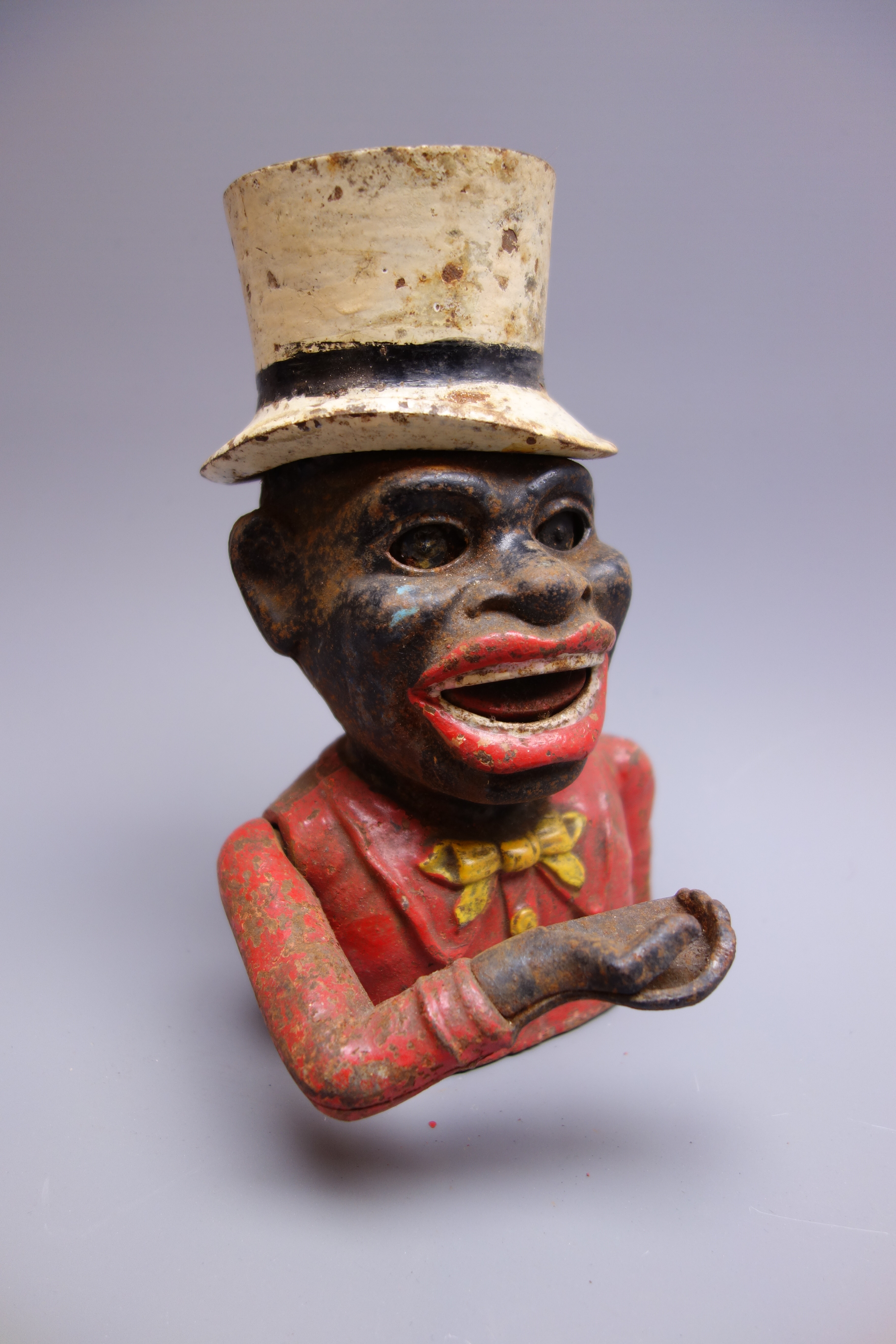 Cast iron mechanical money box as the head and shoulders of a jolly man wearing a white top hat,