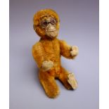 Early 20th century small plush covered figure of a monkey wearing spectacles,
