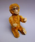 Early 20th century small plush covered figure of a monkey wearing spectacles,