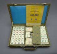 Chinese mah jongg set with bone and bamboo tiles and sticks in decorative cloth covered wooden