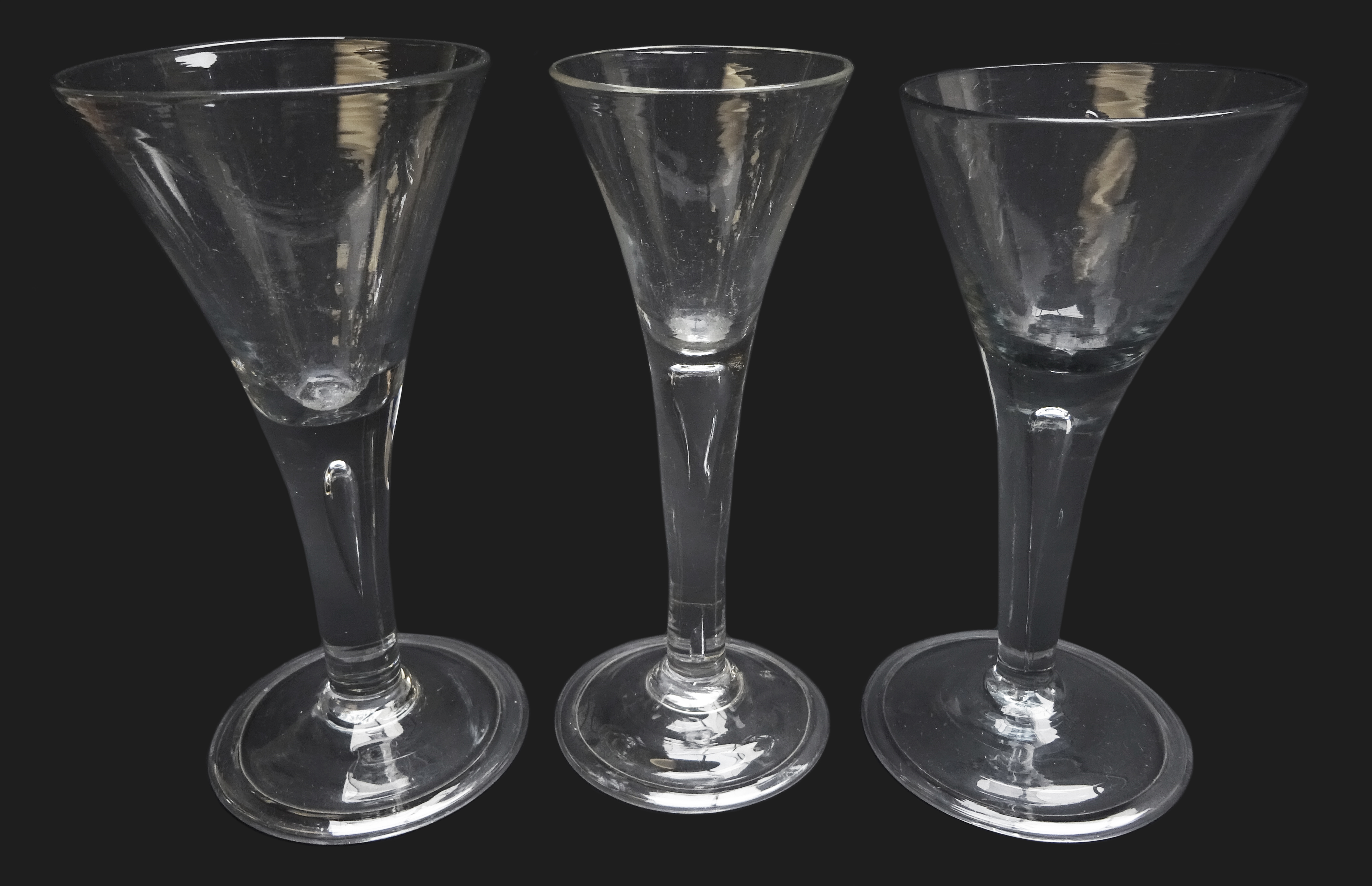 Three wine glasses each with trumpet bowl rising from a thick plain stem enclosing a single tear on