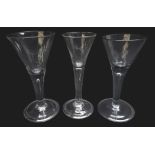 Three wine glasses each with trumpet bowl rising from a thick plain stem enclosing a single tear on