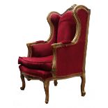 French upholstered wing back chair, the gilt frame with scroll carved cresting and acanthus arms,