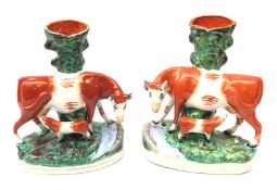 Pair Victorian Staffordshire spill vases each surmounted with the model of a cow and suckling calf,