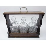 Oak three bottle 'tantalus' style decanter stand with silver-plated mounts and handle,