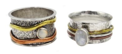 Two silver spinner rings set with a moonstone and an opal,