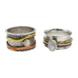 Two silver spinner rings set with a moonstone and an opal,