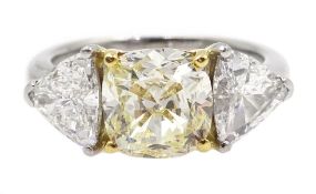 Platinum three stone diamond ring, the centre fancy light yellow cushion cut diamond of approx 1.