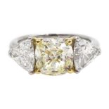 Platinum three stone diamond ring, the centre fancy light yellow cushion cut diamond of approx 1.