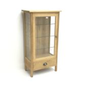 Light oak display cabinet, single door enclosing three glazed shelves, single drawer,