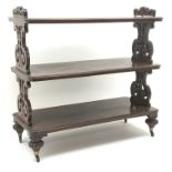 Victorian mahogany three tier dumb waiter, carved and pierced supports on brass castors, W130cm,