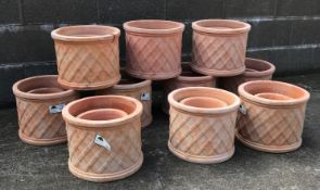 Twenty terracotta cylindrical pots with lattice design,