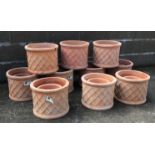 Twenty terracotta cylindrical pots with lattice design,