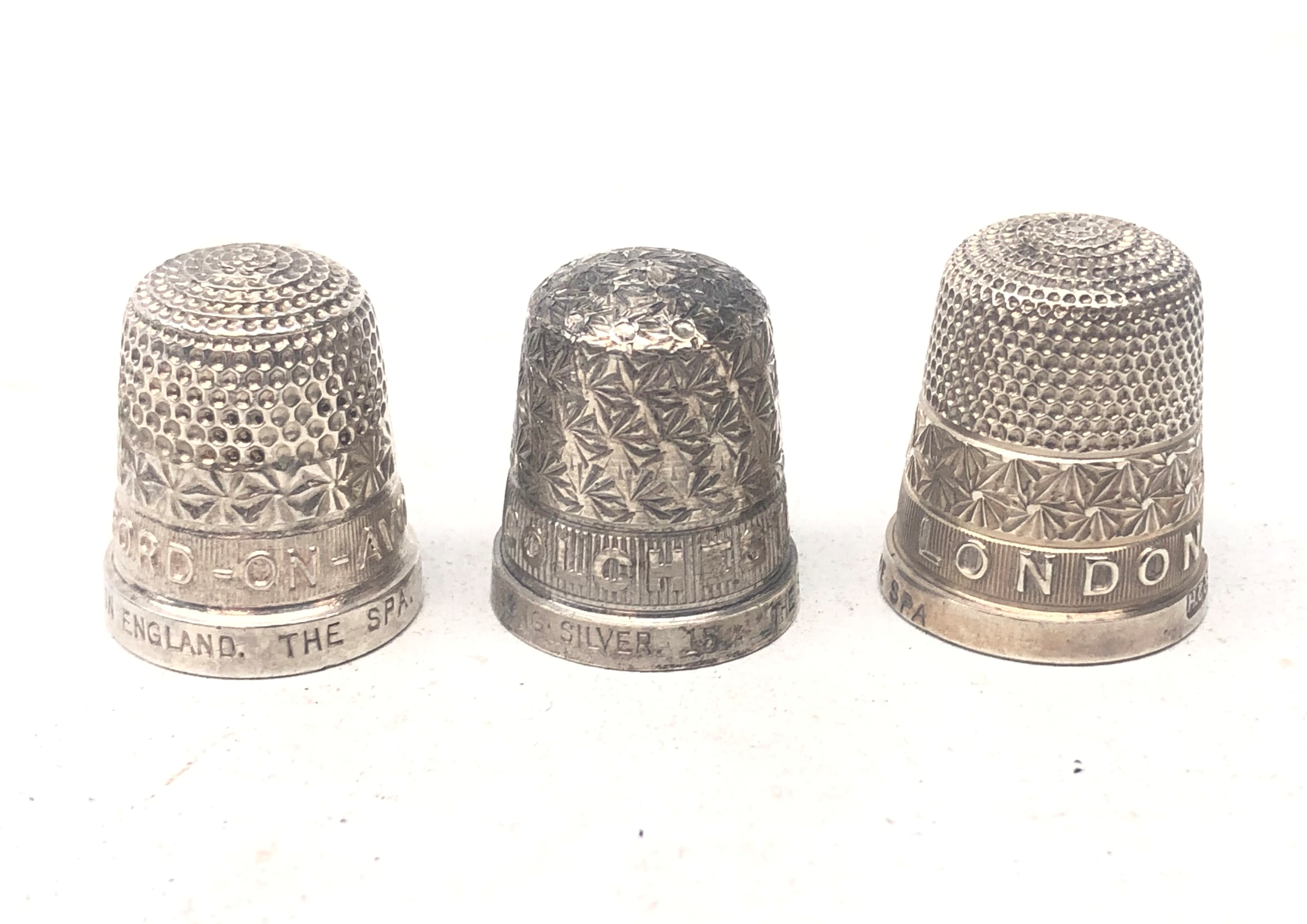 Three 'The Spa' silver thimbles, relief decorated London, Stratford on Avon and Colchester,
