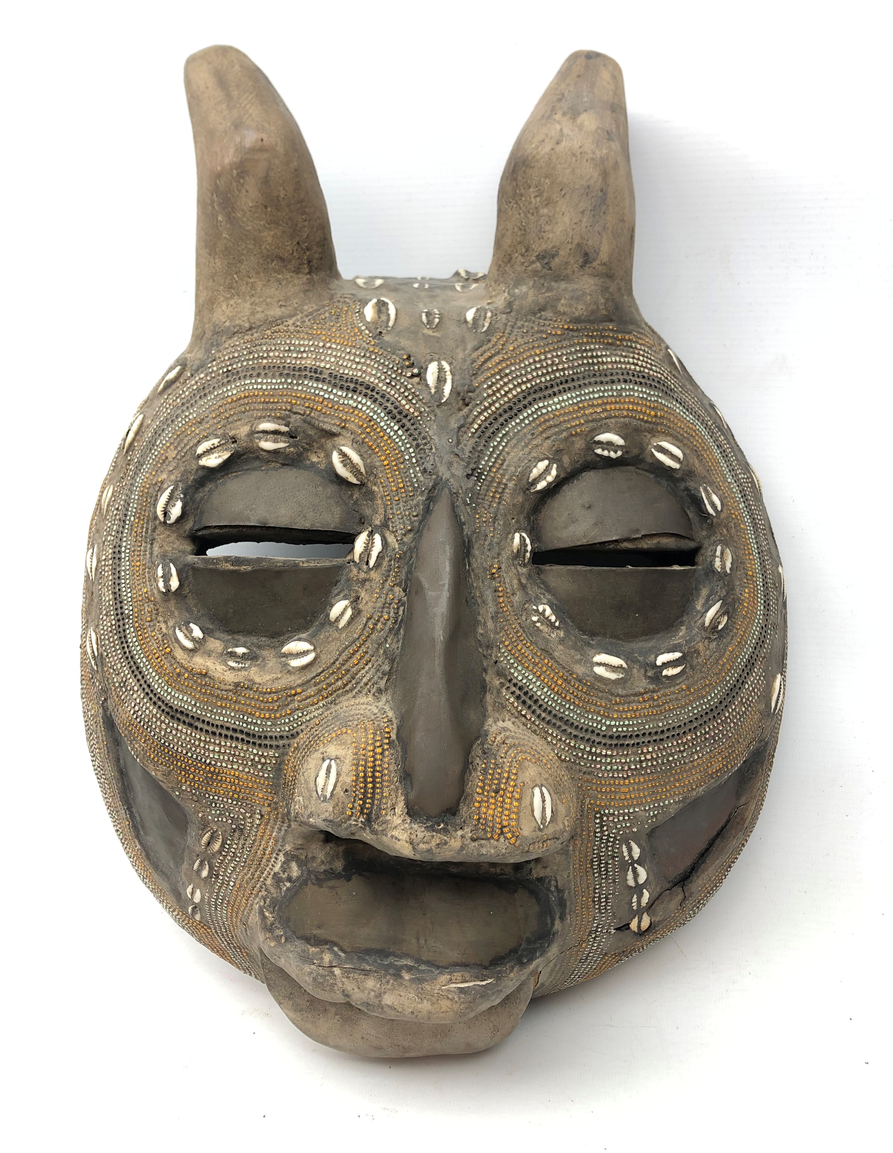 African carved softwood mask with eyes, nose and mouth apertures, inlaid cowrie shells,